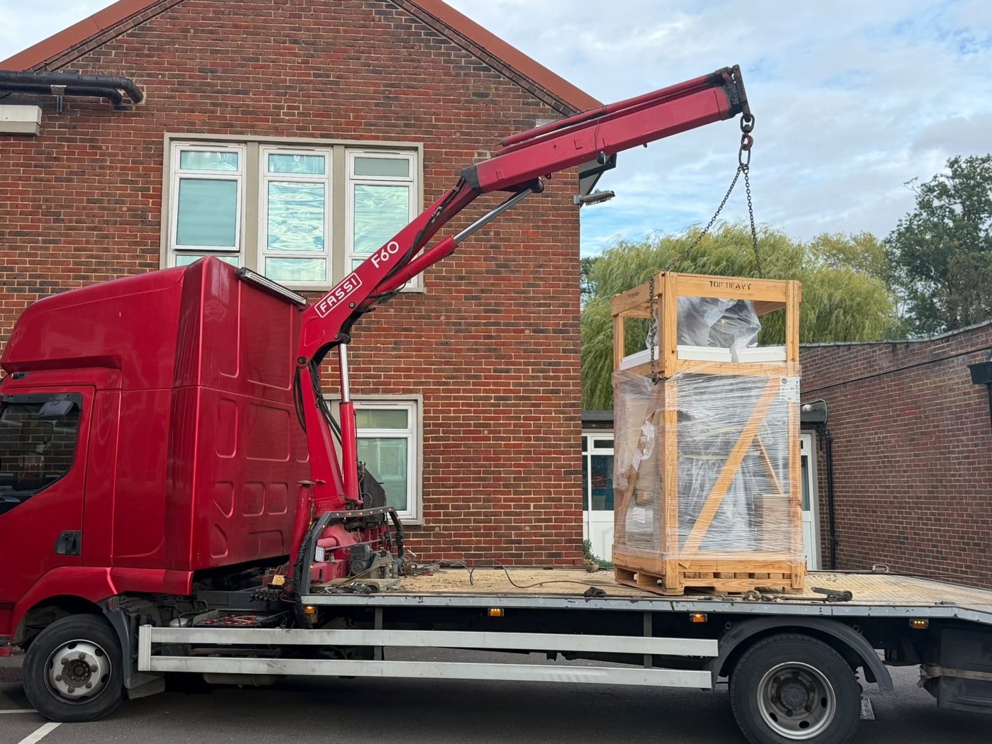 HIAB crane lifting crated equipment onto a truck
