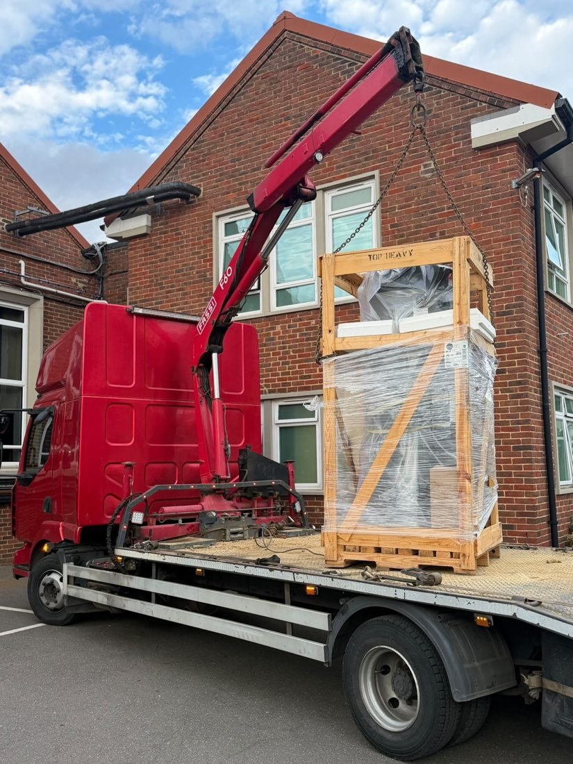 HIAB crane lifting a crated equipment unit