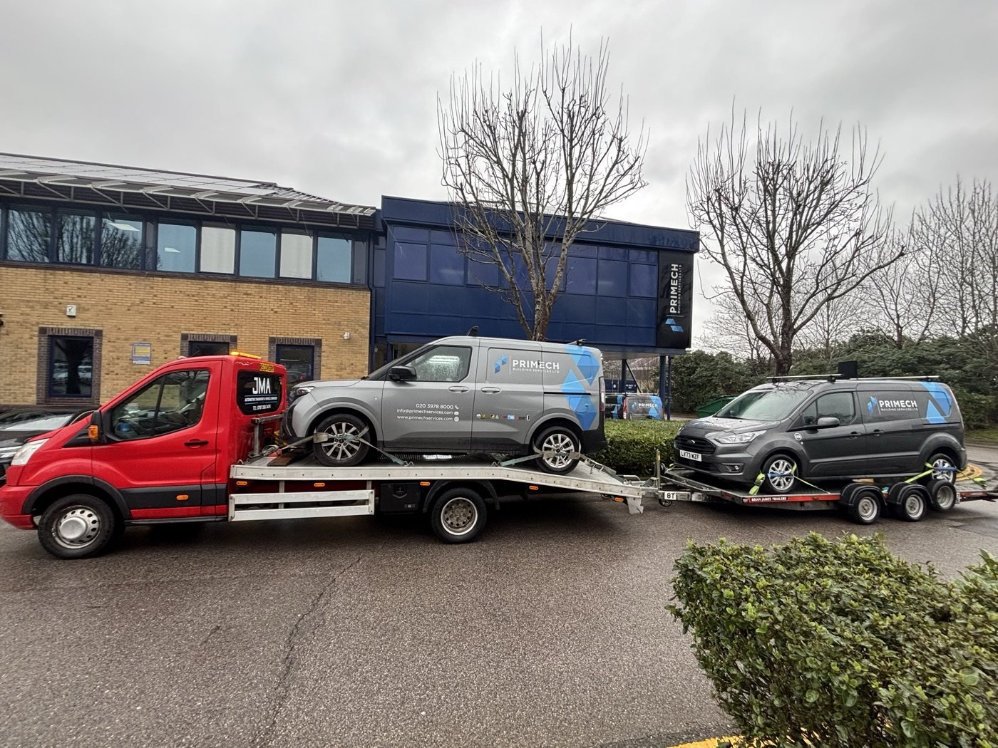 Van and car transported by recovery truck and trailer